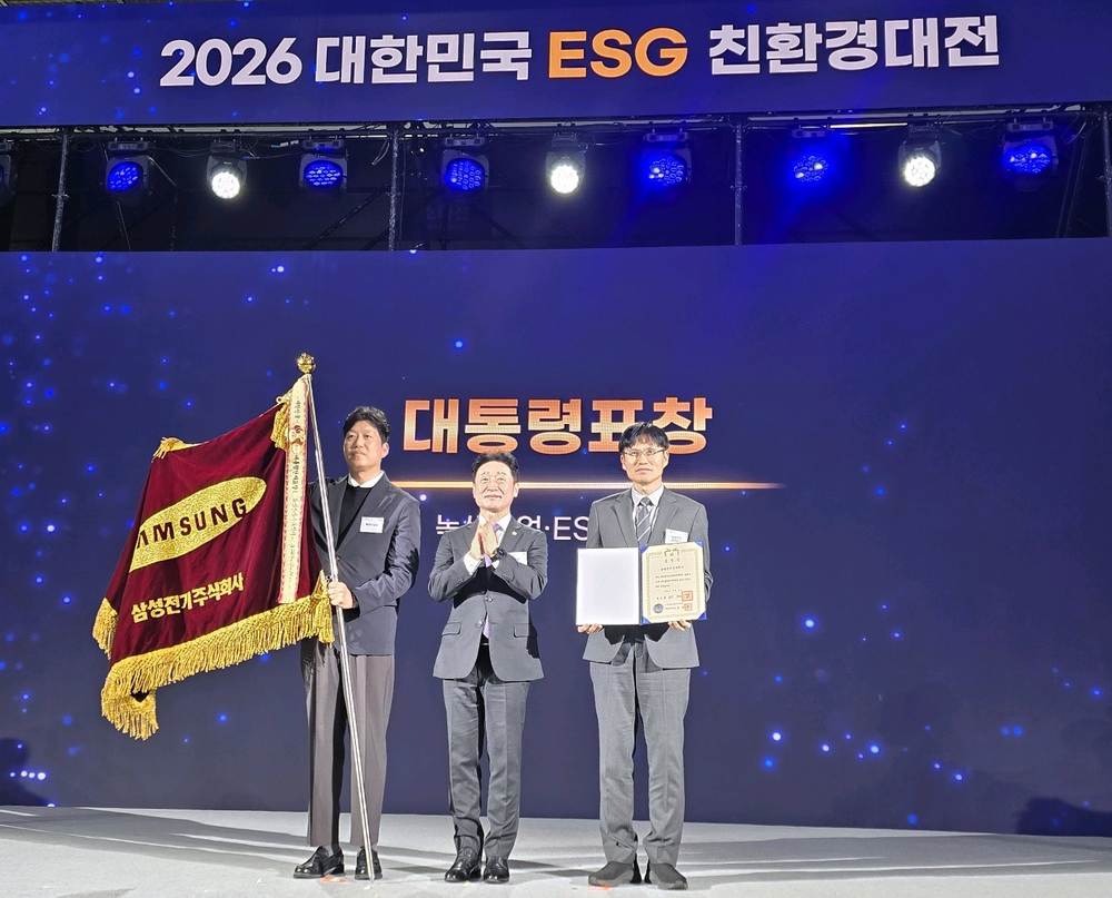 [참고] 대통령표창 문구 앞에서 세 사람이 표창장과 삼성전기 깃발을 들고 기념촬영하고 있다..png
